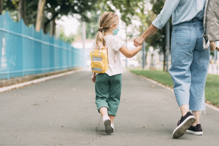 dziecko na chodniku trzymające rodzica za rękę