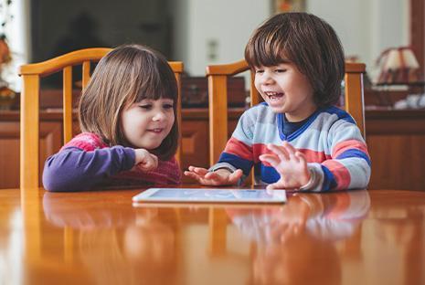 Uśmiechnięte dzieci przy stole z tabletem